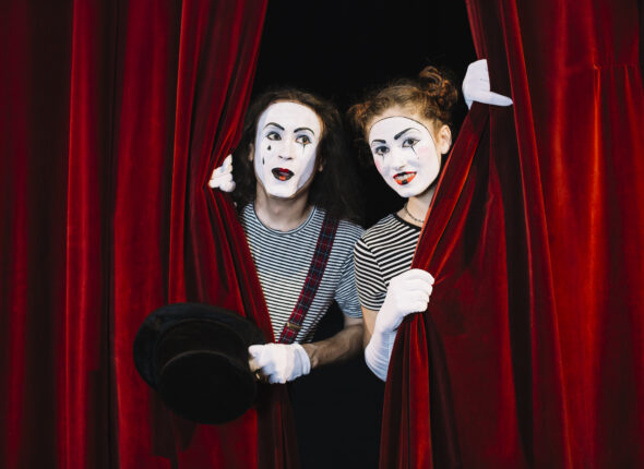 two-mime-artist-peeking-through-red-curtain