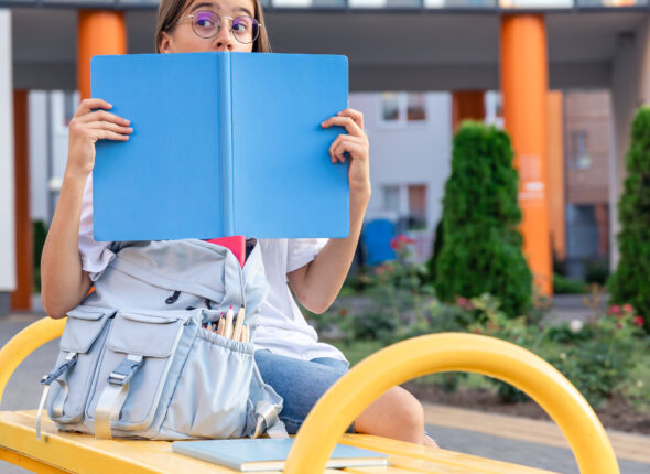 girl-with-backpack-near-school-blue-notebook-background-school