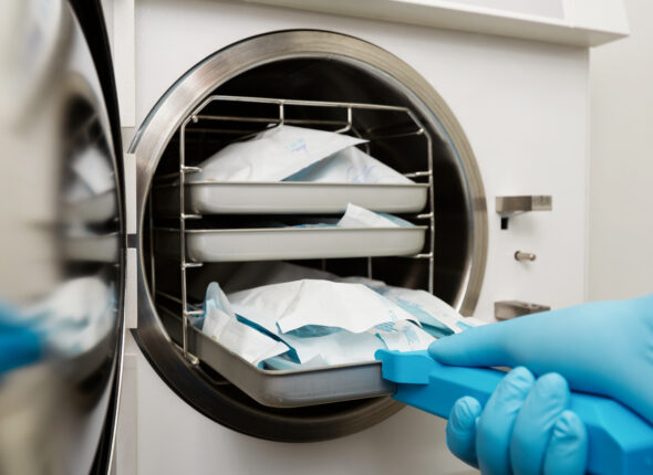 Young male dentist places medical autoclave for sterilising surgical and other instruments